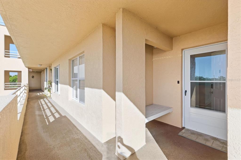 An exterior walkway leads to a white front door with a built-in bench nearby — 4570 PINEBROOK CIRCLE UNIT 503, BRADENTON, FL