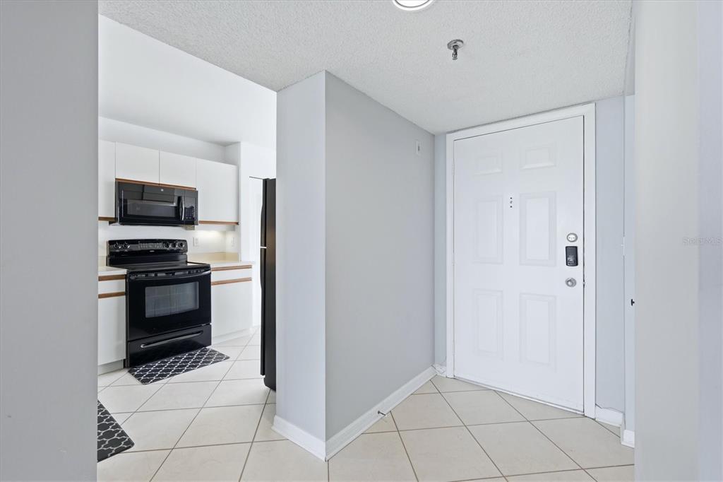 A tiled entryway leads to a kitchen with white cabinets and black appliances — 4570 PINEBROOK CIRCLE UNIT 503, BRADENTON, FL