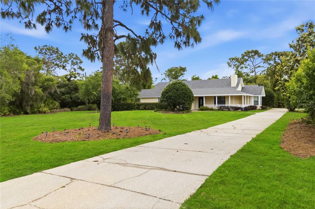 A long concrete driveway leads to a single-story house with a covered front porch — 6928 SAWGRASS DRIVE, ST CLOUD, FL