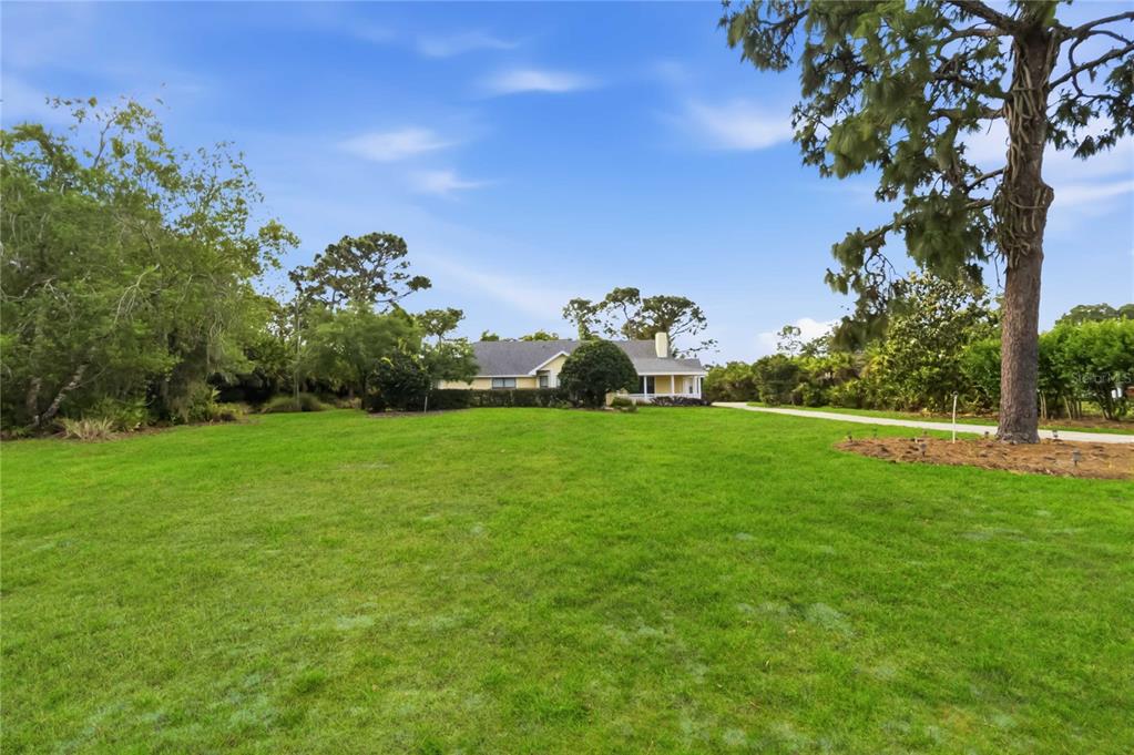 A single-story house with a light-colored exterior sits at the end of a long driveway — 6928 SAWGRASS DRIVE, ST CLOUD, FL