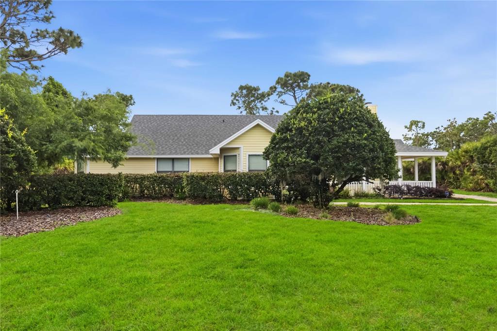 A yellow house with a gray shingled roof sits behind a large green lawn — 6928 SAWGRASS DRIVE, ST CLOUD, FL