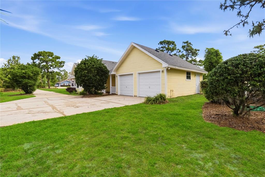 A yellow house with a two-car garage and a concrete driveway sits on a lawn — 6928 SAWGRASS DRIVE, ST CLOUD, FL