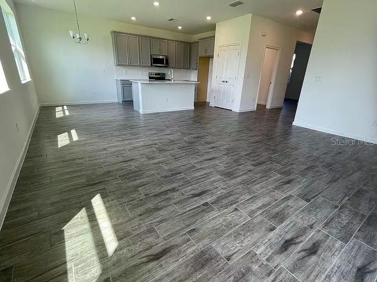 An open-concept kitchen and dining area features gray wood-look tile flooring and white cabinetry — 1365 YORKDALE ROAD, DAVENPORT, FL