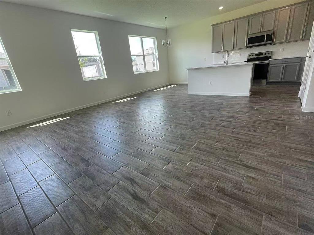 An open-concept kitchen and living area featuring wood-look tile flooring and grey cabinetry — 1365 YORKDALE ROAD, DAVENPORT, FL
