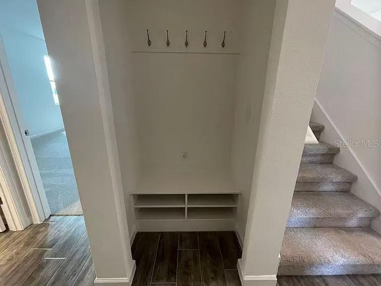 An entryway nook features a built-in bench with shoe storage, wall hooks, and adjacent carpeted stairs — 1365 YORKDALE ROAD, DAVENPORT, FL
