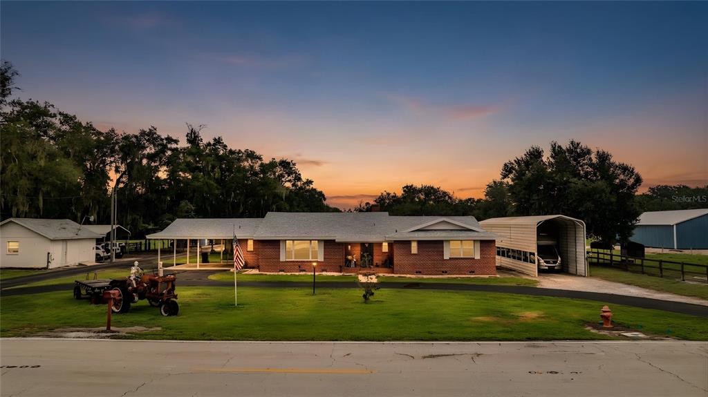 A single-story brick house with a carport and a metal shed at sunset — 1633 CHERRY LANE, LAKELAND, FL