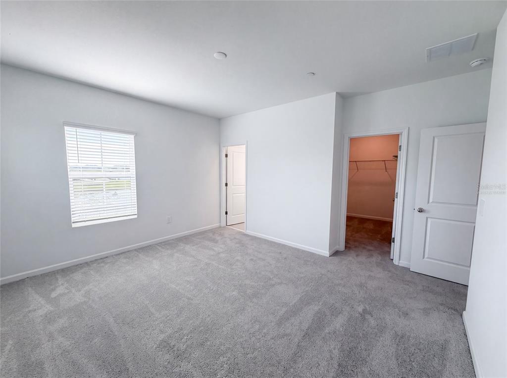 A bedroom with gray carpet, white walls, a window with blinds, and two doorways — 2224 RED SUN STREET, APOPKA, FL