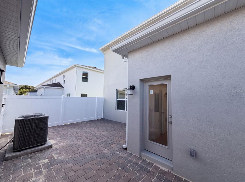 A paved patio area features a gray exterior wall, a glass door, and an AC unit — 2224 RED SUN STREET, APOPKA, FL