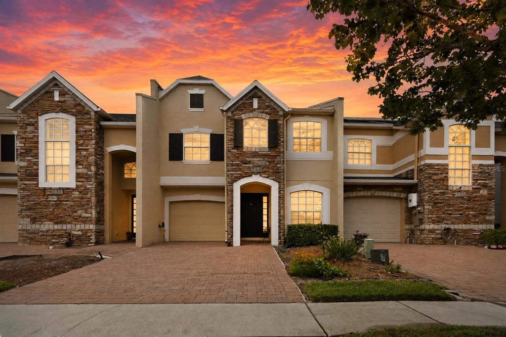 A two-story townhouse with a stone facade, beige stucco, and two attached garages — 534 TERRACE SPRING DRIVE, ORLANDO, FL