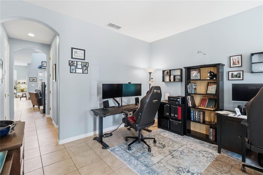 A home office with two desks, gaming chairs, a bookshelf, and a white entry door — 534 TERRACE SPRING DRIVE, ORLANDO, FL