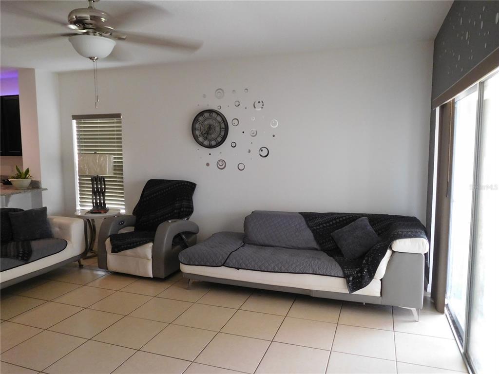 A living room features a white and gray sofa, a matching armchair, and a wall clock — 4767 MARCOS CIRCLE, KISSIMMEE, FL