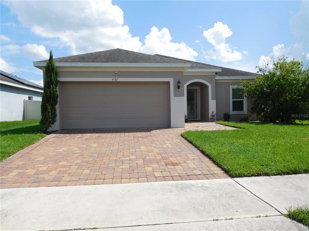 A single-story house with a beige stucco exterior, a paved driveway, and a two-car garage — 4767 MARCOS CIRCLE, KISSIMMEE, FL