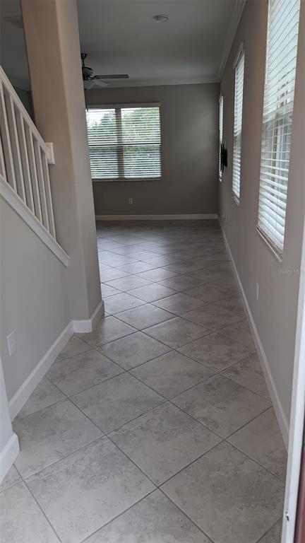 A hallway with diagonal tile flooring leads toward a room with a ceiling fan — 1384 WHITE FOX RUN, LUTZ, FL