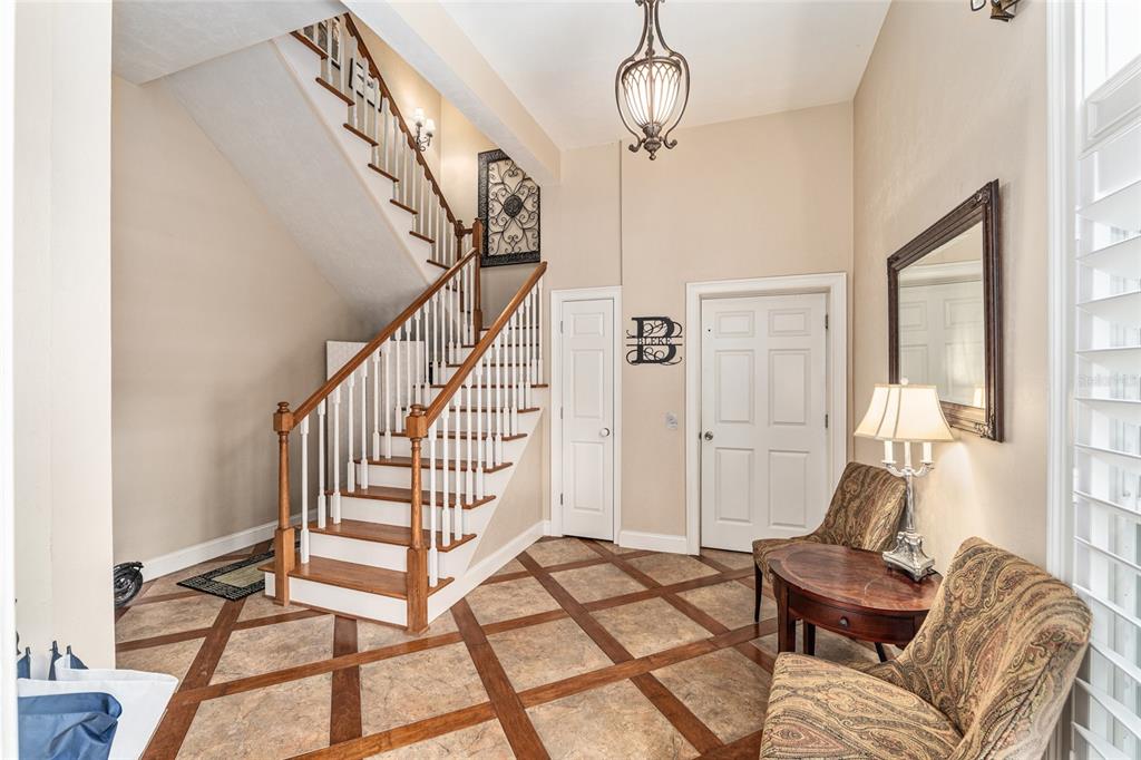 An entryway features a wooden staircase, tiled flooring with wood accents, and two patterned armchairs — 5015 SW 91 TERRACE, GAINESVILLE, FL