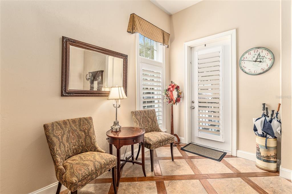 A foyer features two patterned chairs, a small round table, a mirror, and tiled flooring — 5015 SW 91 TERRACE, GAINESVILLE, FL