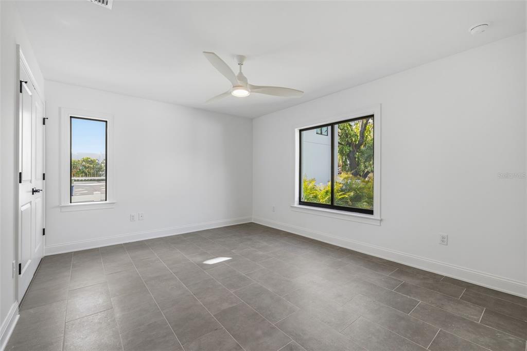 An empty room with white walls, gray tile flooring, a ceiling fan, and two windows — 4509 W NORTH A STREET UNIT 2, TAMPA, FL
