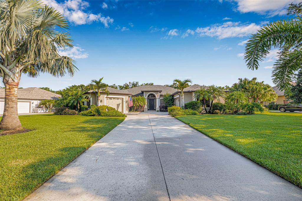 A single-story house with a concrete driveway, palm trees, and a green lawn — 15420 27TH COURT E, PARRISH, FL