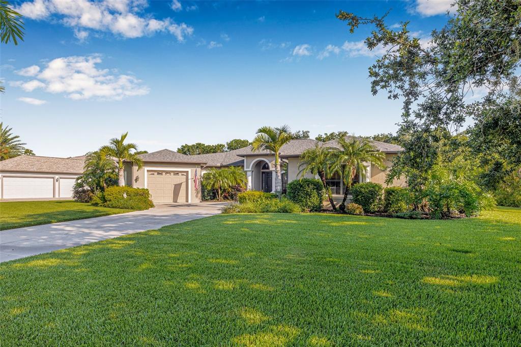 A single-story house with a beige exterior, a multi-car garage, and a large front lawn — 15420 27TH COURT E, PARRISH, FL