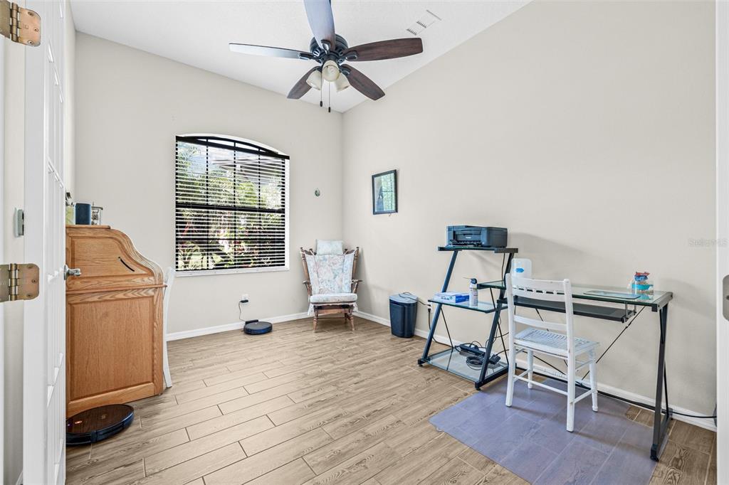 A home office with wood-look tile flooring, a ceiling fan, and a glass desk — 15420 27TH COURT E, PARRISH, FL