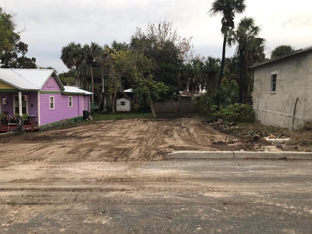 A vacant, cleared dirt lot sits between a purple house and a concrete block building — 750 6TH STREET, CEDAR KEY, FL