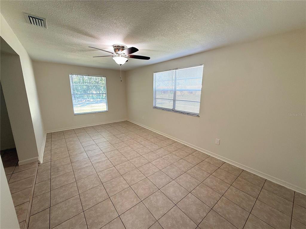 A room with light-colored walls, tiled flooring, a ceiling fan, and a large window — 101 S FLAMINGO AVENUE, WINTER SPRINGS, FL