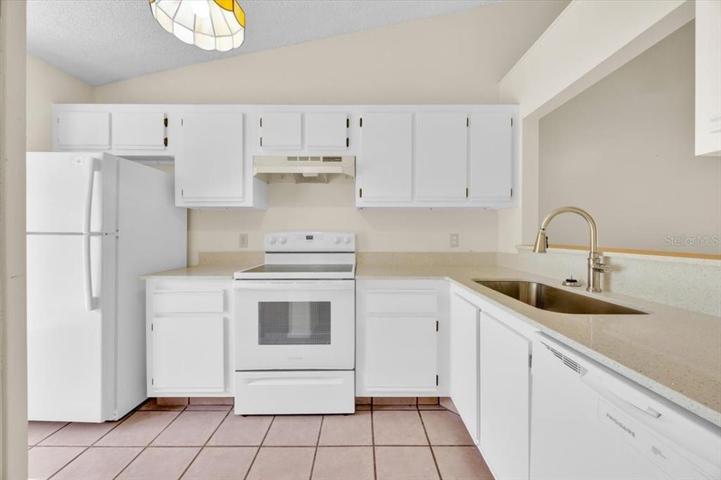 A kitchen features white cabinets, white appliances, a light countertop, and tiled flooring — 2907 PRINCE OAK COURT, ST CLOUD, FL