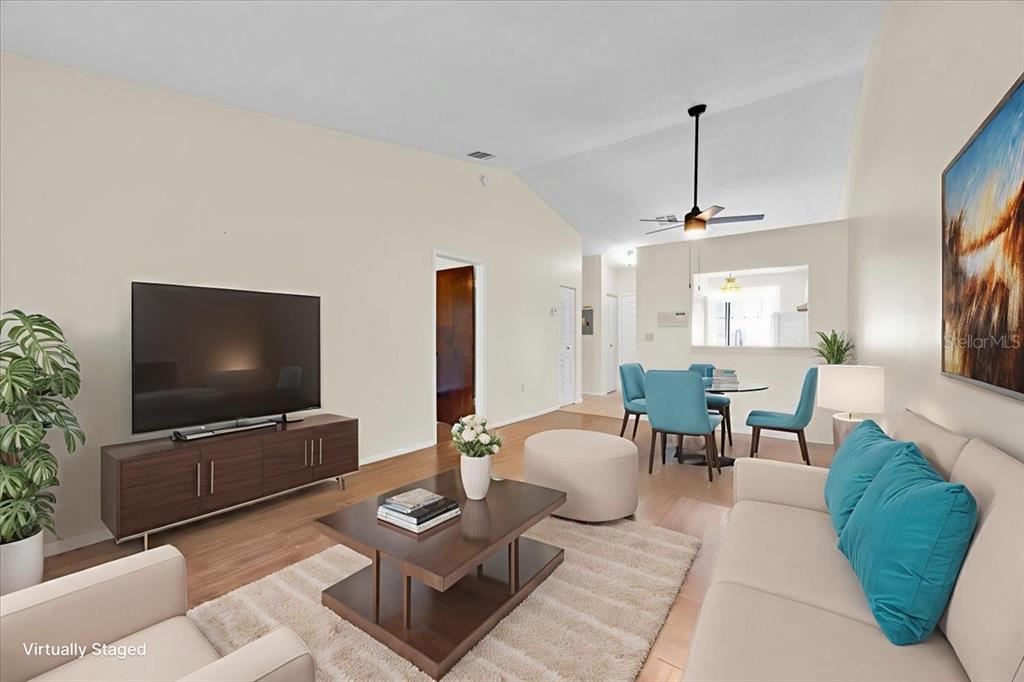 A living room with a vaulted ceiling, wood-look flooring, and a dining area in the background — 2907 PRINCE OAK COURT, ST CLOUD, FL