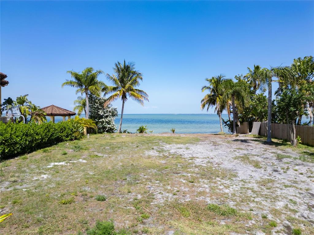 A grassy, sandy waterfront lot features palm trees and a view of the ocean — 1013 SYMPHONY ISLES BOULEVARD, APOLLO BEACH, FL