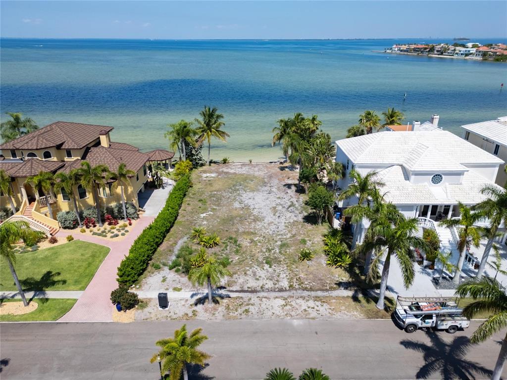An aerial view shows a vacant waterfront lot situated between two large residential homes — 1013 SYMPHONY ISLES BOULEVARD, APOLLO BEACH, FL