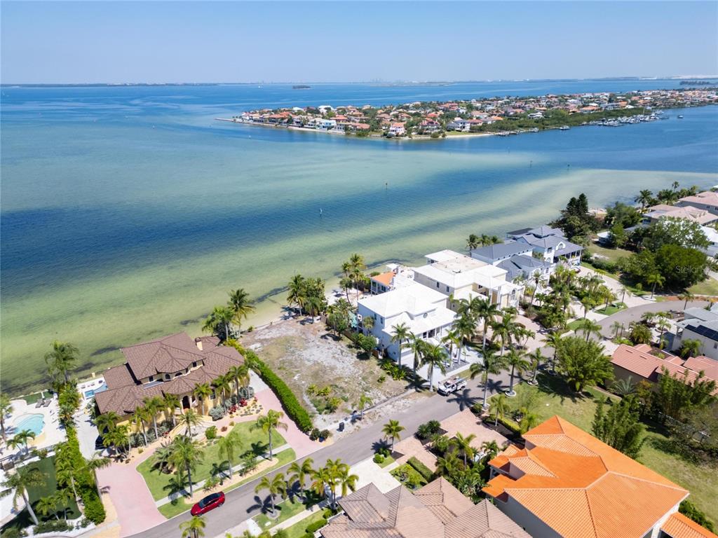 An aerial view shows a vacant waterfront lot situated between two large residential homes — 1013 SYMPHONY ISLES BOULEVARD, APOLLO BEACH, FL