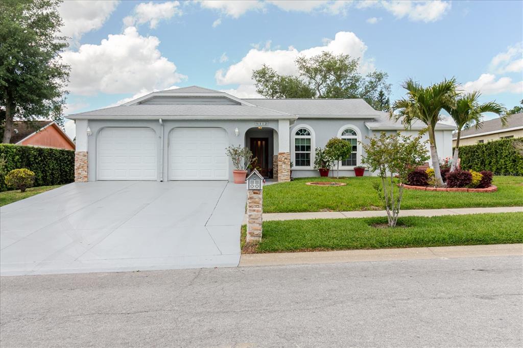 A single-story house with a two-car garage, gray exterior, and a front lawn — 8112 GOLDEN BEAR LOOP, PORT RICHEY, FL