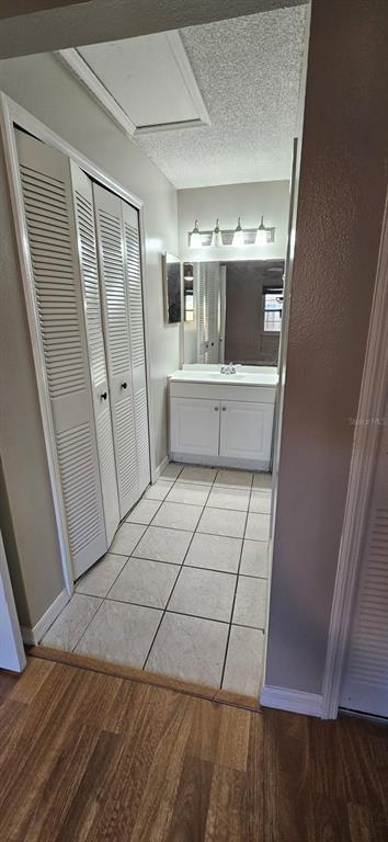 A bathroom vanity area with white cabinets, a mirror, and tiled flooring — 2227 MARGARITA COURT UNIT 2227, KISSIMMEE, FL