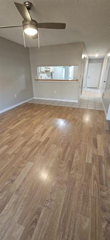 A living area with wood-look flooring, a ceiling fan, and a pass-through window to the kitchen — 2227 MARGARITA COURT UNIT 2227, KISSIMMEE, FL
