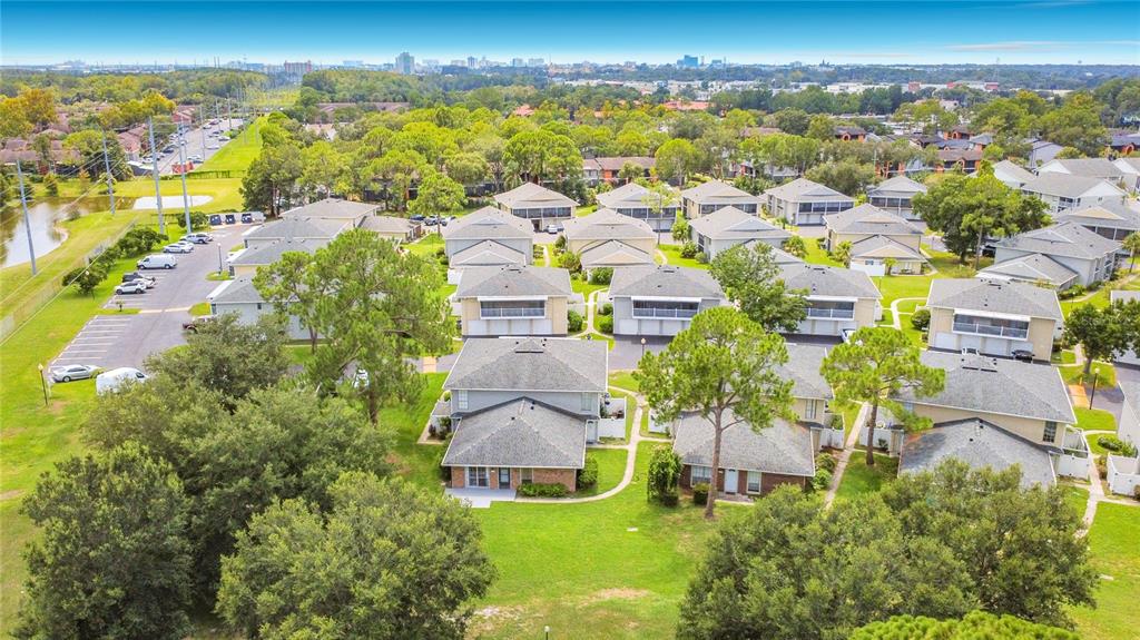 An aerial view of a residential complex with multiple townhouses, green lawns, and parking areas — 4375 SHADOW CREST PLACE UNIT 34-1, ORLANDO, FL