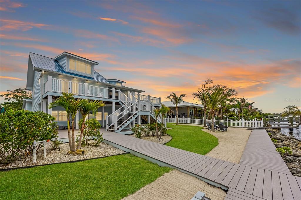 A two-story coastal house with a metal roof, elevated deck, and wooden walkway by water — 17 VIP A ISLAND, GRANT, FL