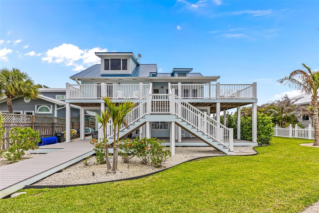 An elevated coastal house features a large wooden deck, white railings, and a central staircase — 17 VIP A ISLAND, GRANT, FL