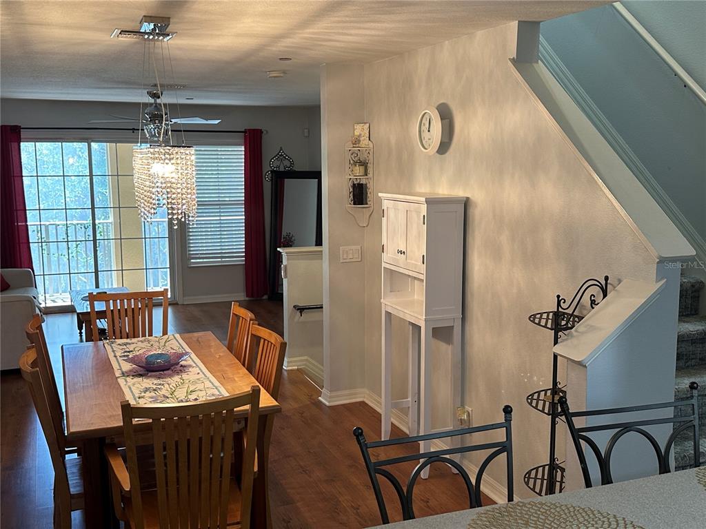 A dining area with a wooden table, crystal chandelier, and a white cabinet near stairs — 8809 WHITE SAGE LOOP, LAKEWOOD RANCH, FL