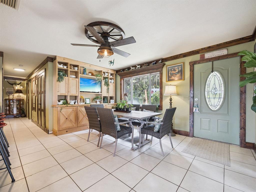 A dining room features a wagon wheel ceiling fan, built-in wooden cabinetry, and tile flooring — 6001 MARTHAS LANE, ST CLOUD, FL