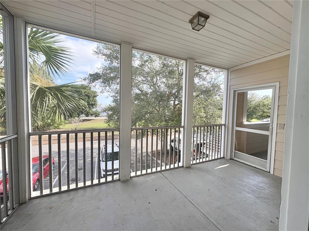 A screened-in balcony with a concrete floor, white railings, and a view of a parking lot — 4802 51ST STREET W UNIT 1016, BRADENTON, FL