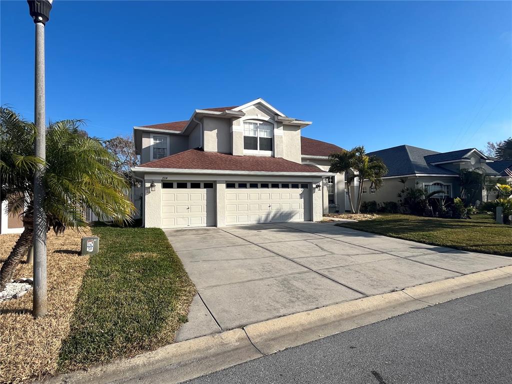 A two-story house with a two-car garage and a concrete driveway under a clear sky — 1914 OSWEGO DRIVE, HOLIDAY, FL