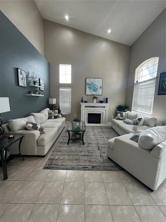 A living room features a vaulted ceiling, a fireplace, and light-colored tile flooring — 1914 OSWEGO DRIVE, HOLIDAY, FL