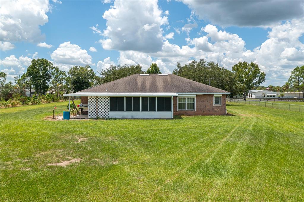 The rear exterior of a brick house features a screened-in porch and a large lawn — 270 KEEN ROAD, FROSTPROOF, FL