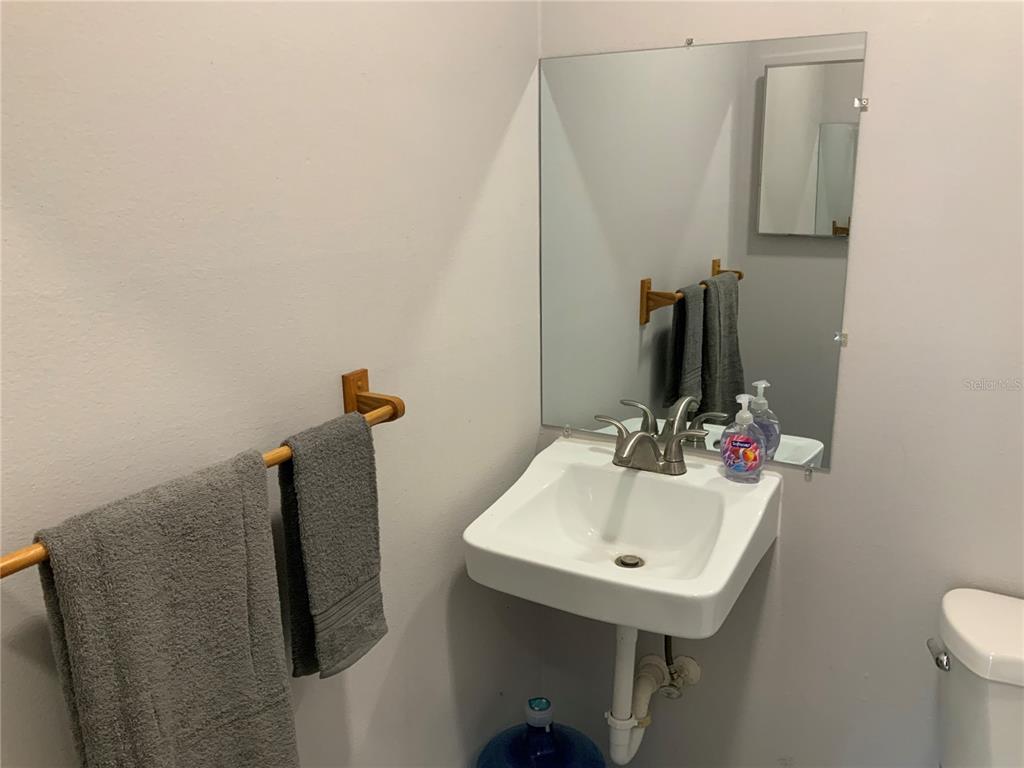 A bathroom features a wall-mounted sink, a large mirror, and gray towels on a rack — 2417 GUAVA DRIVE UNIT 1, EDGEWATER, FL