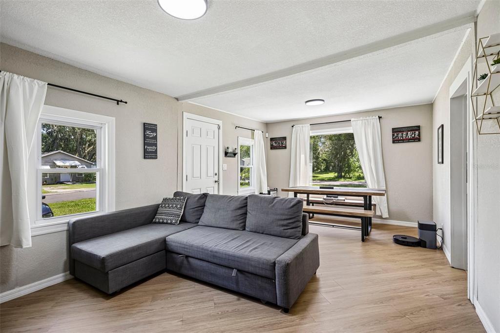A living room features a gray sectional sofa, a dining table, and light wood flooring — 1903 N BARNES STREET, PLANT CITY, FL