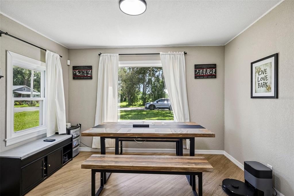 A dining room features a wooden table with benches, white curtains, and light wood flooring — 1903 N BARNES STREET, PLANT CITY, FL