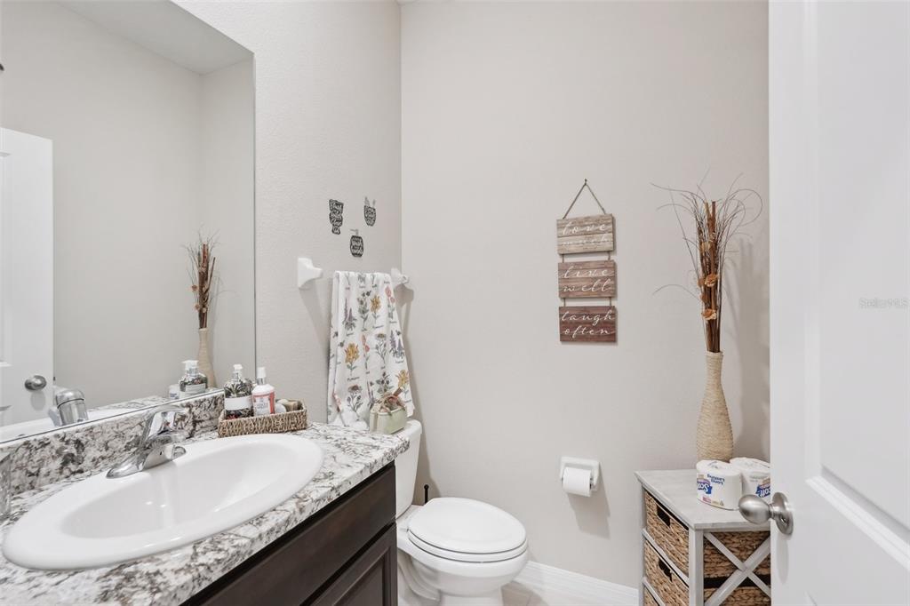 A small bathroom features a granite vanity, a white toilet, and wall-mounted decorative signs — 13055 WILLOW GROVE DRIVE, RIVERVIEW, FL