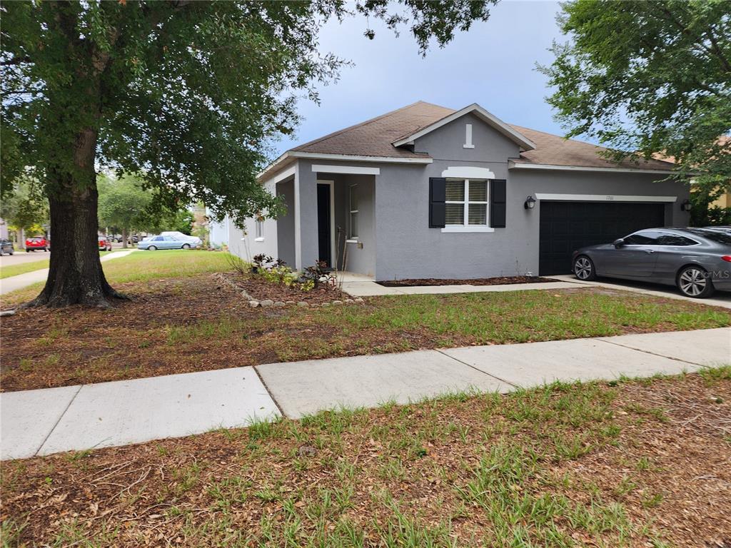 A gray single-story house with a black garage door and a front yard with trees — 1701 CHALKSAND WAY, RUSKIN, FL