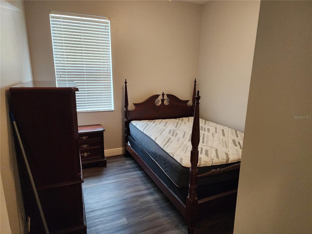 A bedroom features a dark wood four-poster bed, a matching nightstand, and wood-look flooring — 1701 CHALKSAND WAY, RUSKIN, FL