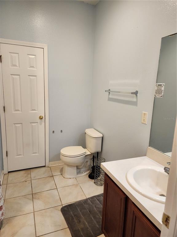 A bathroom features a white toilet, a vanity with a sink, and light-colored tile flooring — 1701 CHALKSAND WAY, RUSKIN, FL