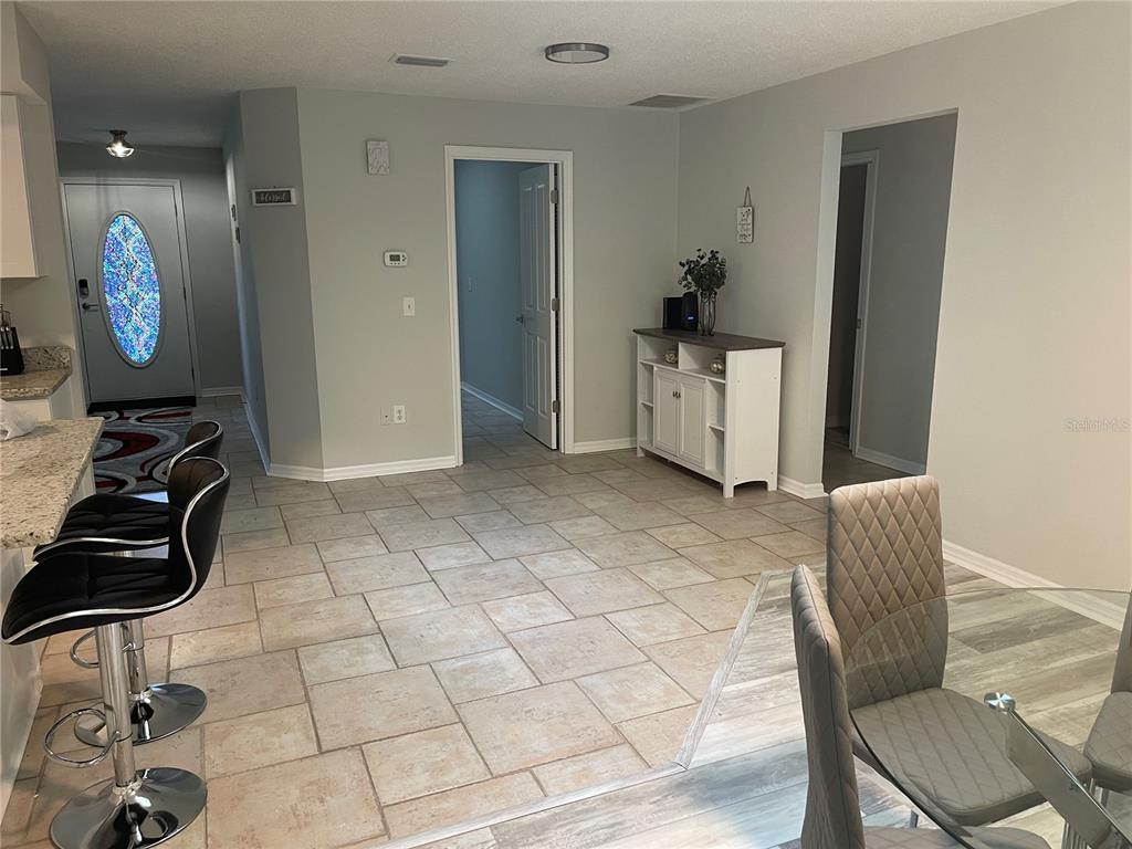 An open-concept dining and kitchen area features tile flooring, a white console table, and barstools — 21 POST VIEW DRIVE, PALM COAST, FL